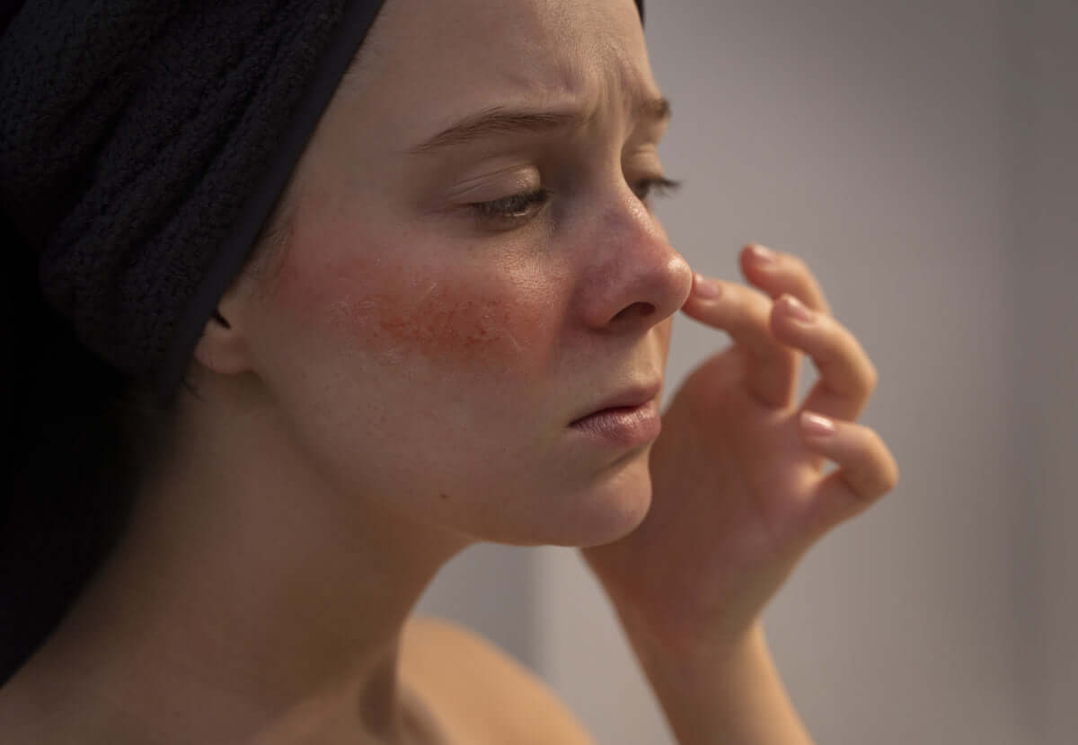 Woman gently touching her face, showing soft, calm skin after following sensitive skin care routine