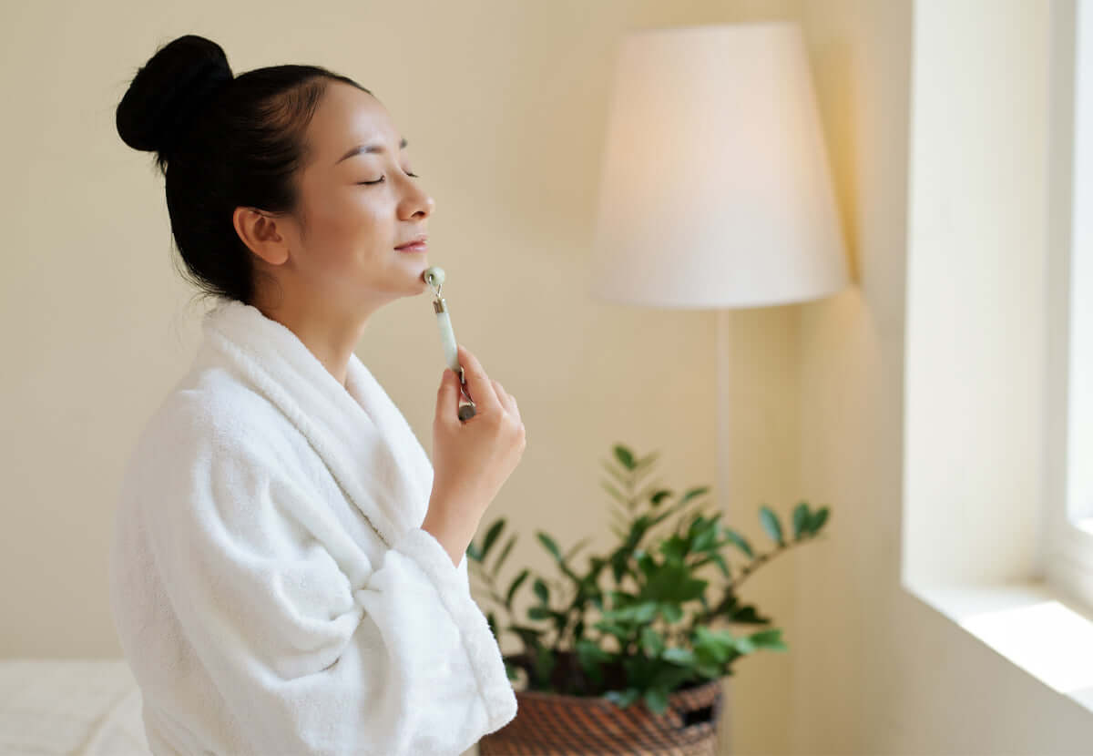 Person in a soft robe holding skincare products, representing a calming self-care ritual